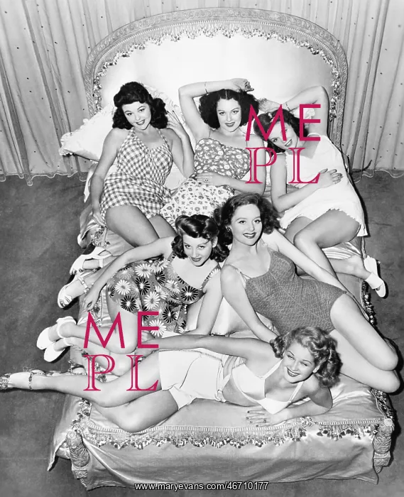 : Six smiling young women lying on a bed : Six smiling young women lying on a bed
