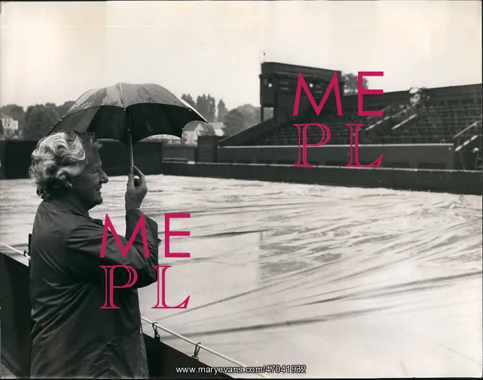 : Spectator in rain at Wimbledon with small umbrella : Spectator in rain at Wimbledon with small umbrella