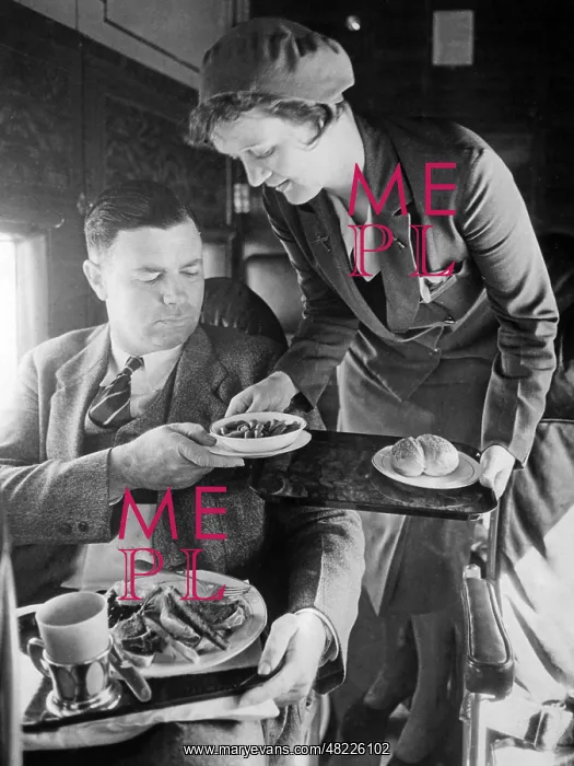 : Stewardess serving dinner aboard an airplane, 1932 : Stewardess serving dinner aboard an airplane, 1932
