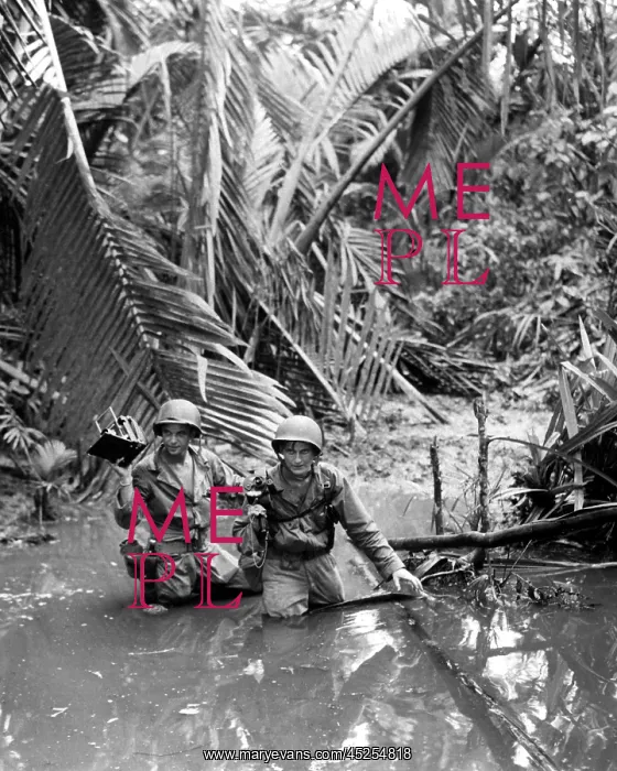 : U.S. Army photographer, wading through a stream : U.S. Army photographer, wading through a stream
