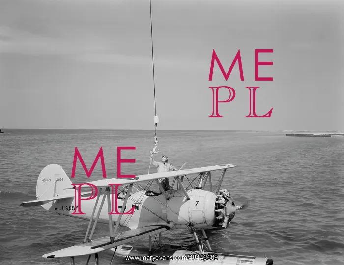 : A U.S. Navy N3N seaplane being attached to : A U.S. Navy N3N seaplane being attached to
