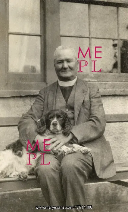  : Vicar with a spaniel dog on a bench