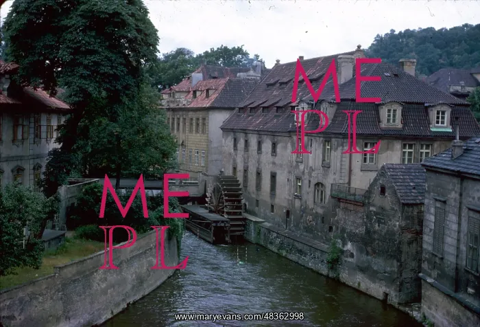 : View of a river with buildings and waterwheel : View of a river with buildings and waterwheel