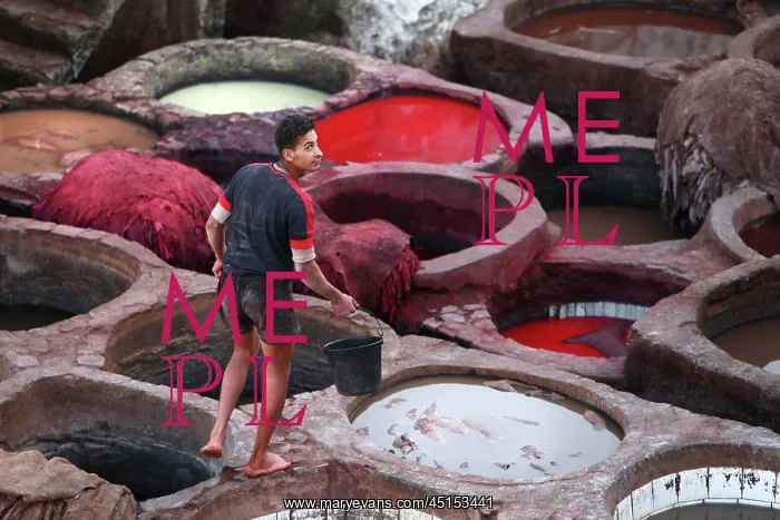 : Fez. View from behind of worker with bucket amongst the dyeing pits : Fez. View from behind of worker with bucket amongst the dyeing pits