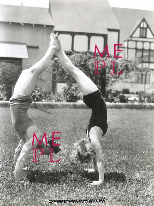 : Side view of young couple doing handstands in yard : Side view of young couple doing handstands in yard