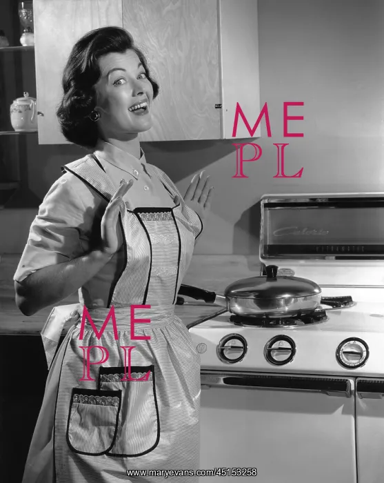 : Woman in her cooking apron in her kitchen smiling : Woman in her cooking apron in her kitchen smiling