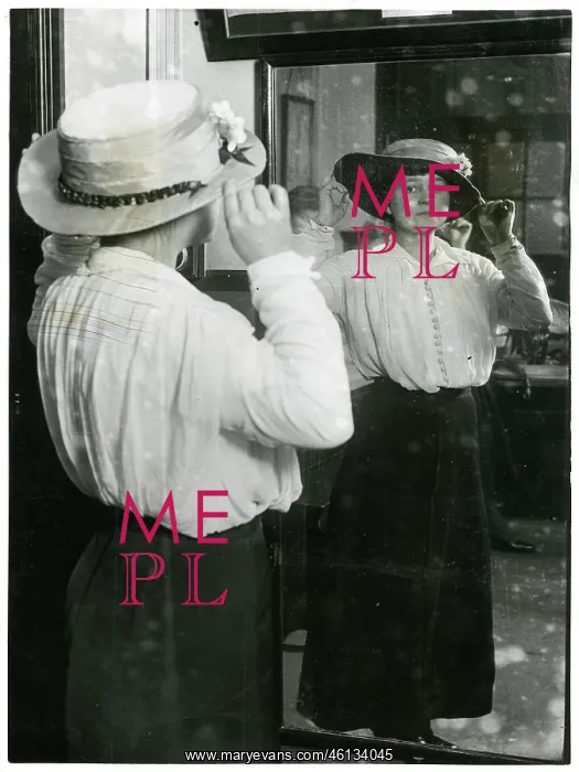 : Woman examining her hat in a mirror : Woman examining her hat in a mirror