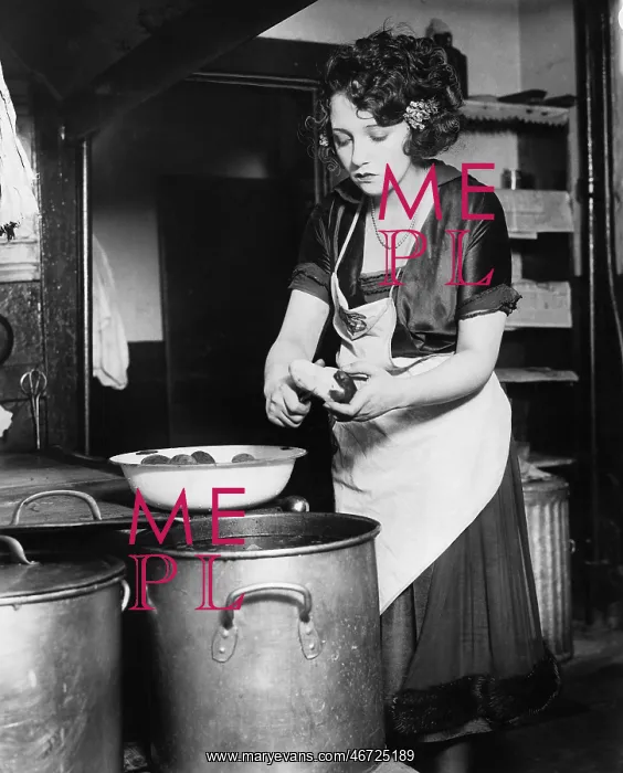  : Woman in a kitchen peeling potatoes