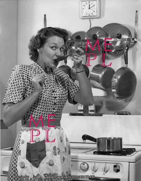 : Woman in kitchen taste testing her cooking : Woman in kitchen taste testing her cooking