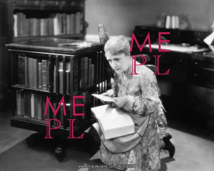 : Woman kneeling with a book in her library finding a letter : Woman kneeling with a book in her library finding a letter