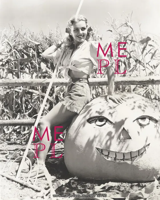 : Woman leaning on large jack o'lantern on farm : Woman leaning on large jack o'lantern on farm