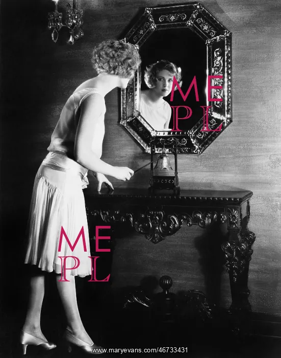 : Woman looking into a mirror about to ring a bell : Woman looking into a mirror about to ring a bell