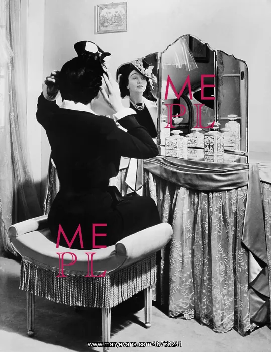 : Woman putting on a hat in front of a dressing table : Woman putting on a hat in front of a dressing table