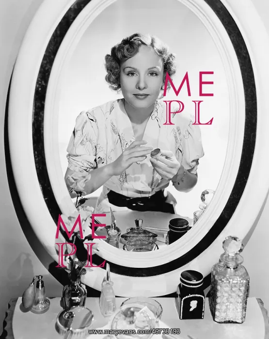 : Woman sitting in front of her vanity looking into : Woman sitting in front of her vanity looking into