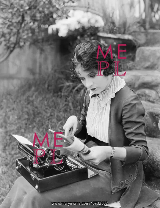 : Woman sitting in the yard with a typewriter on her lap : Woman sitting in the yard with a typewriter on her lap