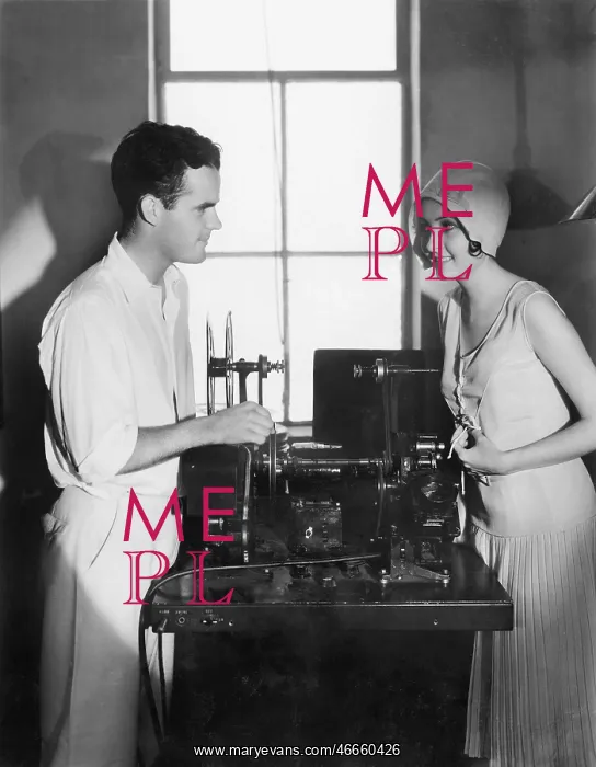 : Woman smiling at a man next to an editing machine : Woman smiling at a man next to an editing machine
