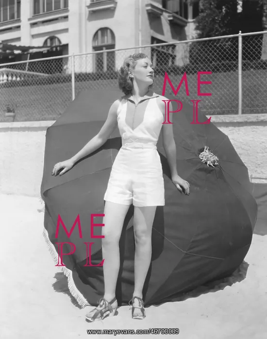 : Woman standing in front of beach umbrella on beach : Woman standing in front of beach umbrella on beach