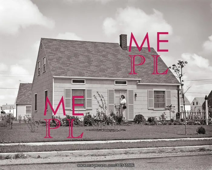 : Woman Standing at Front Door of Frame House in : Woman Standing at Front Door of Frame House in