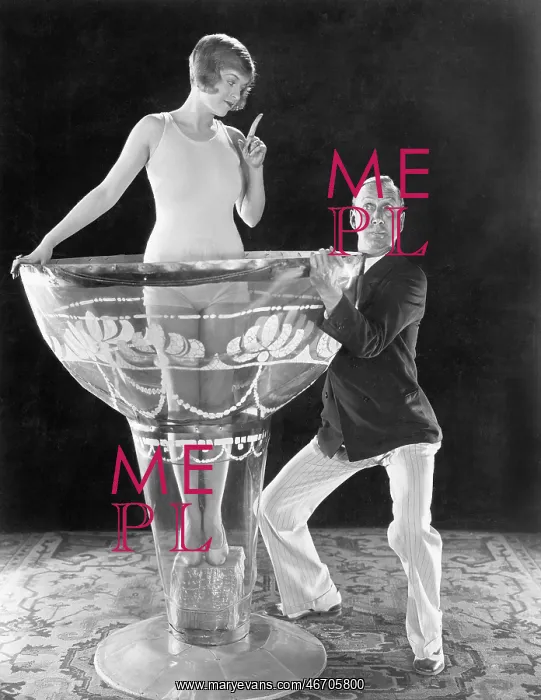 : Woman standing in an oversized glass with a man : Woman standing in an oversized glass with a man