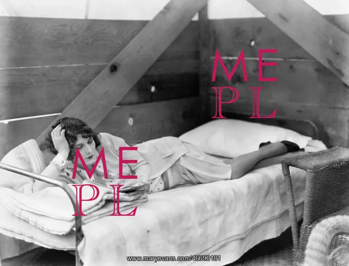  : Woman stretched out on a cot reading a book