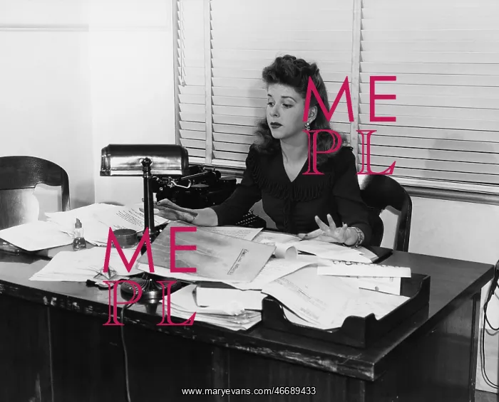 : Woman working at desk covered in papers : Woman working at desk covered in papers