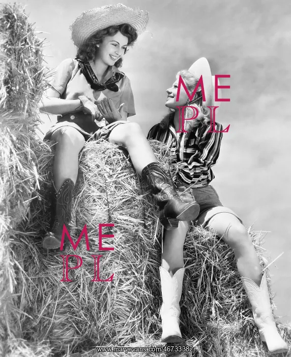 : Two women in cowboy hats sitting on a haystack : Two women in cowboy hats sitting on a haystack