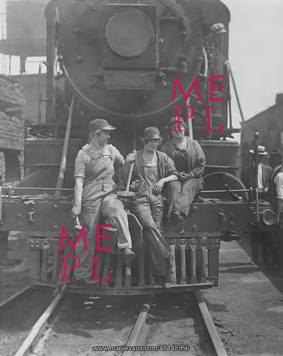 : Women laborers seated on front of engine at : Women laborers seated on front of engine at