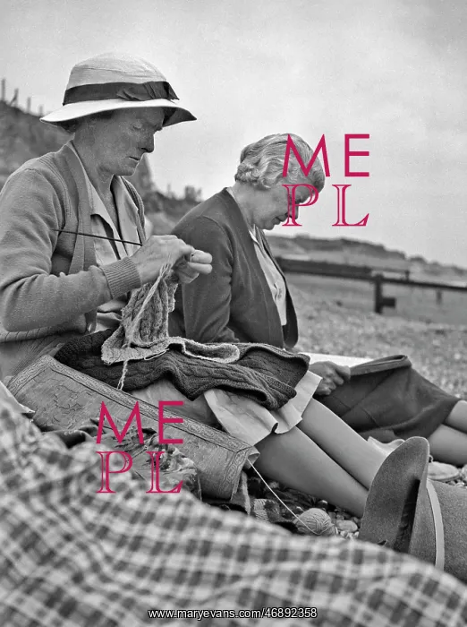 : Two women sitting on a beach : Two women sitting on a beach