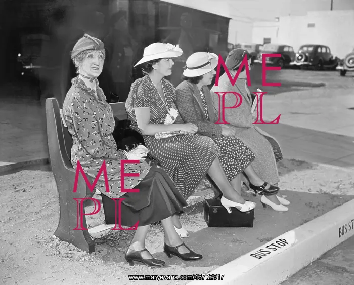 : Four women sitting on a bench waiting for the bus : Four women sitting on a bench waiting for the bus