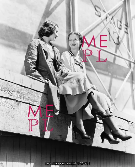 : Two women sitting together on scaffolding : Two women sitting together on scaffolding