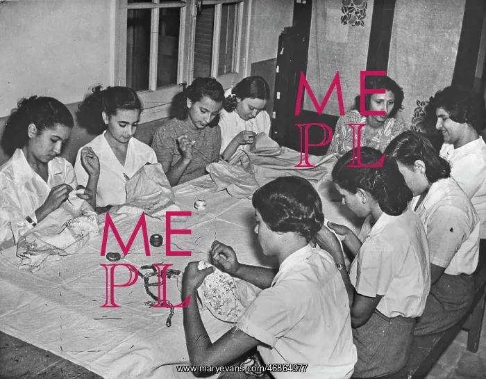 : Women sitting at a table sewing : Women sitting at a table sewing