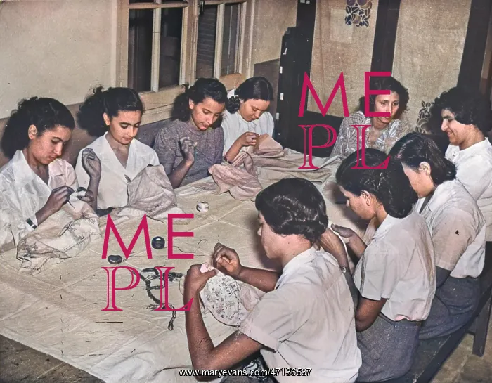 : Women sitting at a table sewing : Women sitting at a table sewing