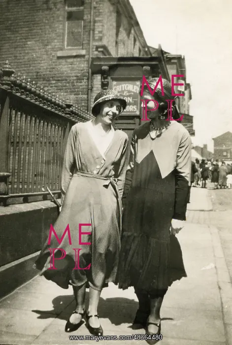 : Two women walking together along a street : Two women walking together along a street