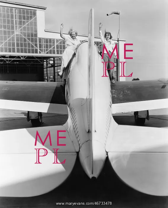 : Two women waving from the wings of a plane : Two women waving from the wings of a plane