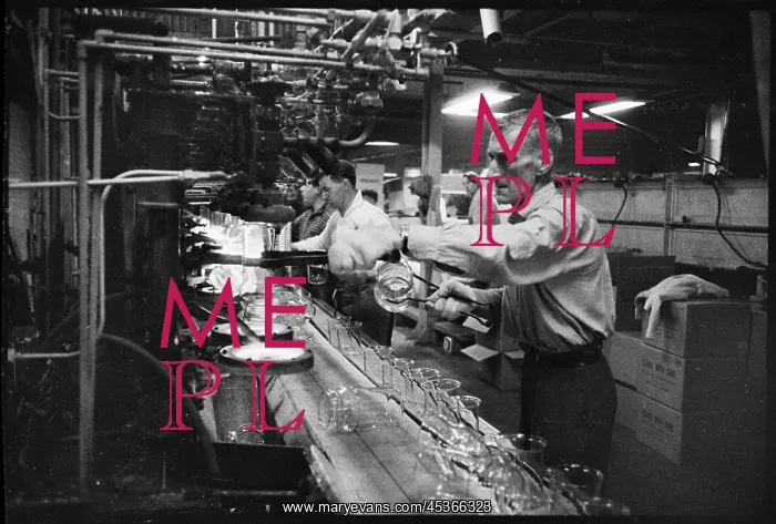 : A worker handling heated beakers and jars on a : A worker handling heated beakers and jars on a