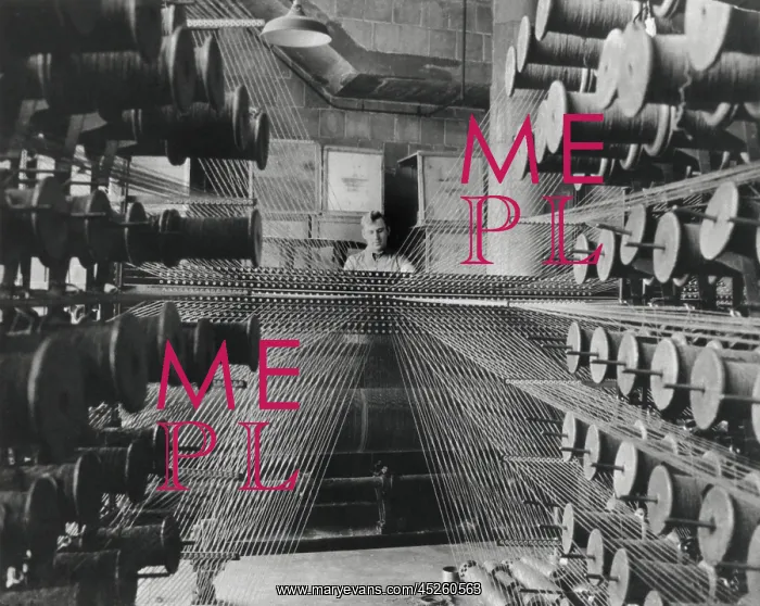 : Workman operating an industrial loom strung with : Workman operating an industrial loom strung with