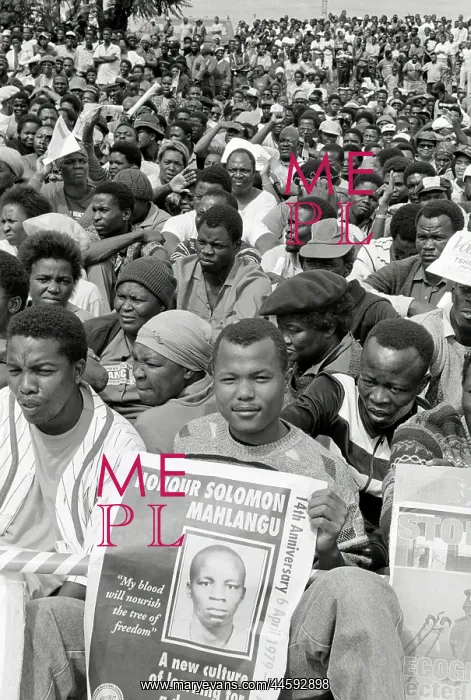 : A young black man sits at the front of a crowd : A young black man sits at the front of a crowd