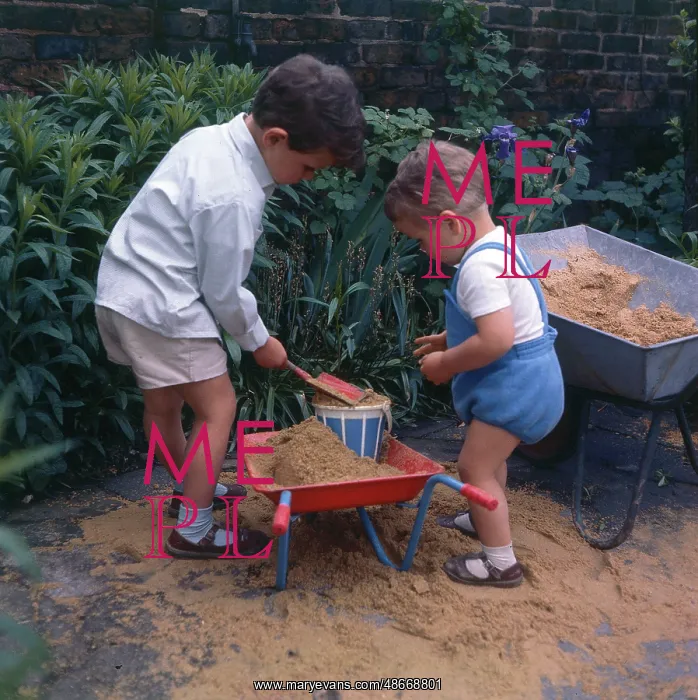  : Two young boys playing with sand and their wheelbarrows