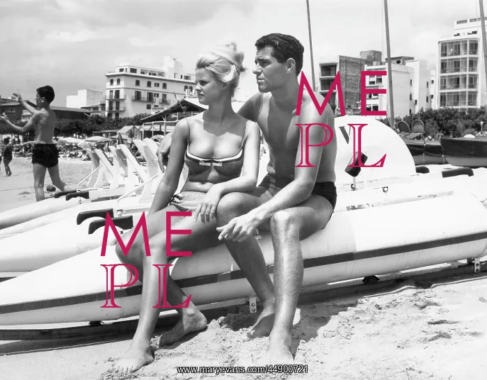 : Young couple sitting on the beach looking out to sea : Young couple sitting on the beach looking out to sea