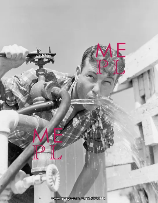 : Young man drinking water from hose : Young man drinking water from hose