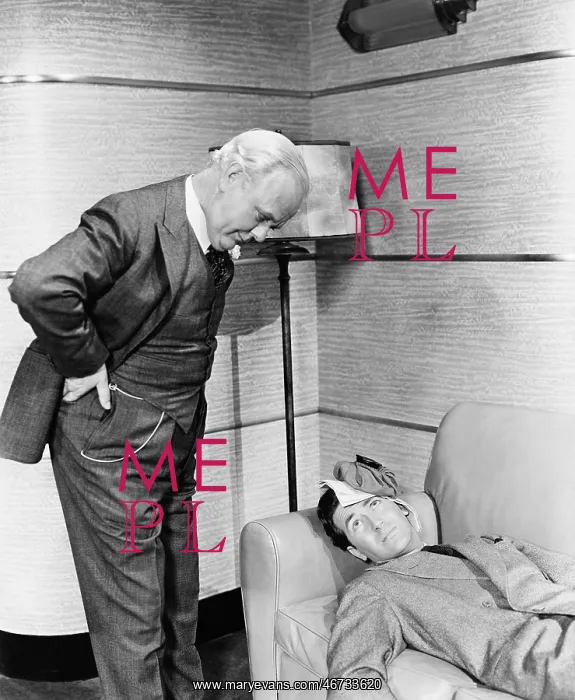 : Young man lying on a couch with a man looking at him : Young man lying on a couch with a man looking at him