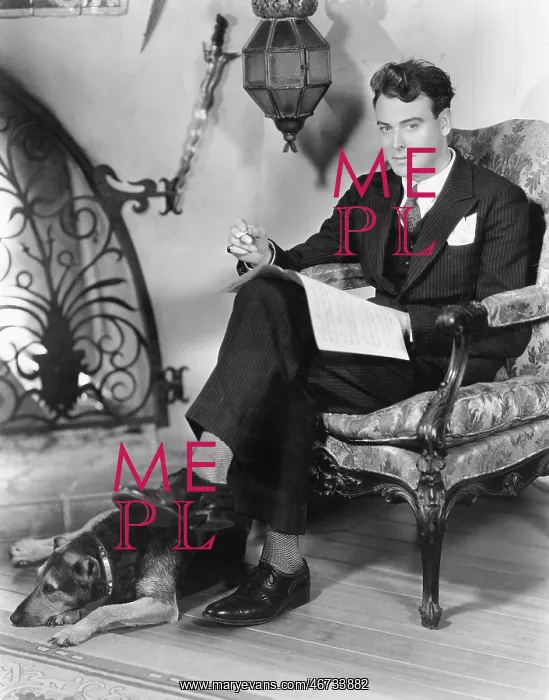 : Young man sitting in an armchair next to a fire : Young man sitting in an armchair next to a fire