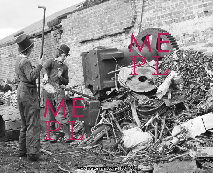 : Two young men sorting through a pile of scrap metal : Two young men sorting through a pile of scrap metal