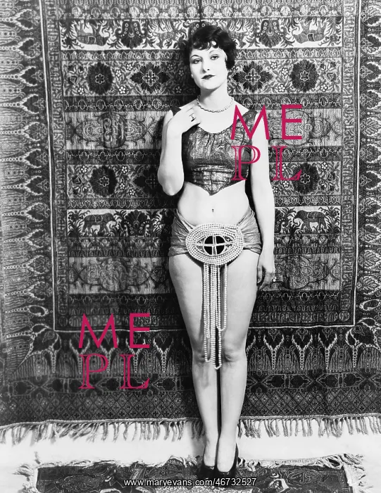  : Young woman barely dressed in front of a hanging carpet
