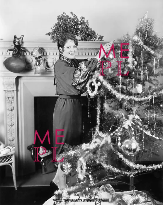 : Young woman decorating a Christmas tree : Young woman decorating a Christmas tree