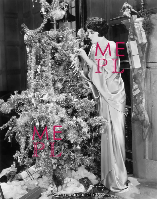 : Young woman decorating a Christmas tree : Young woman decorating a Christmas tree