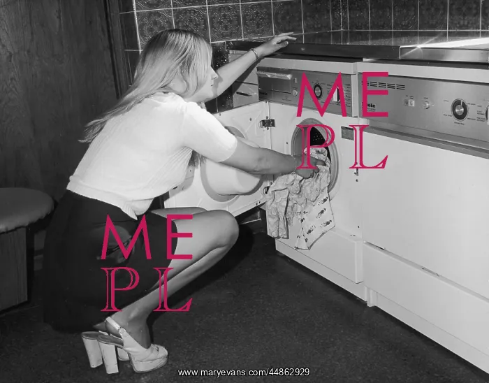 : Young woman loading a washing machine : Young woman loading a washing machine