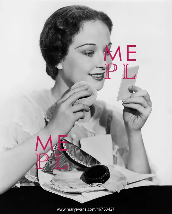 : Young woman looking into a mirror and putting on make up : Young woman looking into a mirror and putting on make up