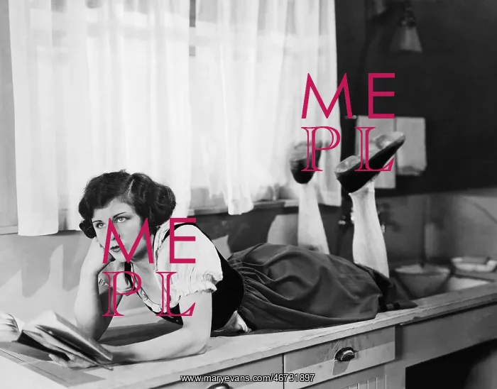 : Young woman lying on a kitchen counter holding a : Young woman lying on a kitchen counter holding a