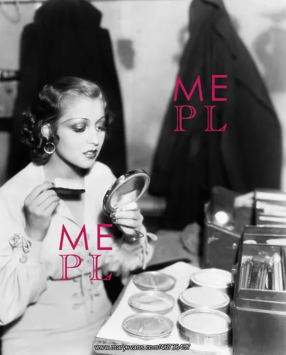 : Young woman with a make up brush looking at her : Young woman with a make up brush looking at her